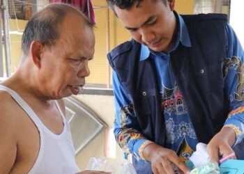 Si Ajo saat mengantarkan obat ke rumah pasien. Mitha.