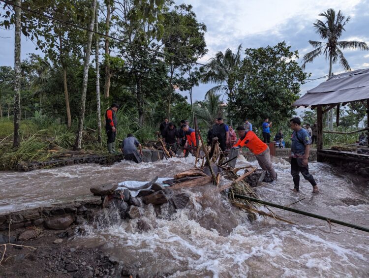 Tim gabungan membersihkan material kayu yang menyumbat jembatan desa akibat banjir bandang menerjang Desa Gunungsari, Kabupaten Bondowoso. IST