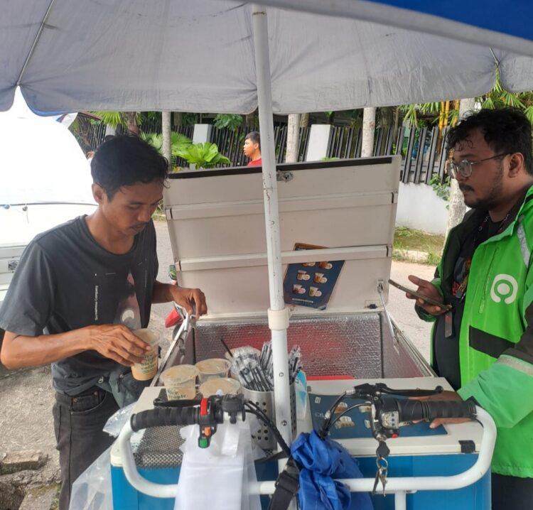 Bima, seorang penjajal kopi gerobak tengah melayani pembeli. KIKI NOFRIJUM